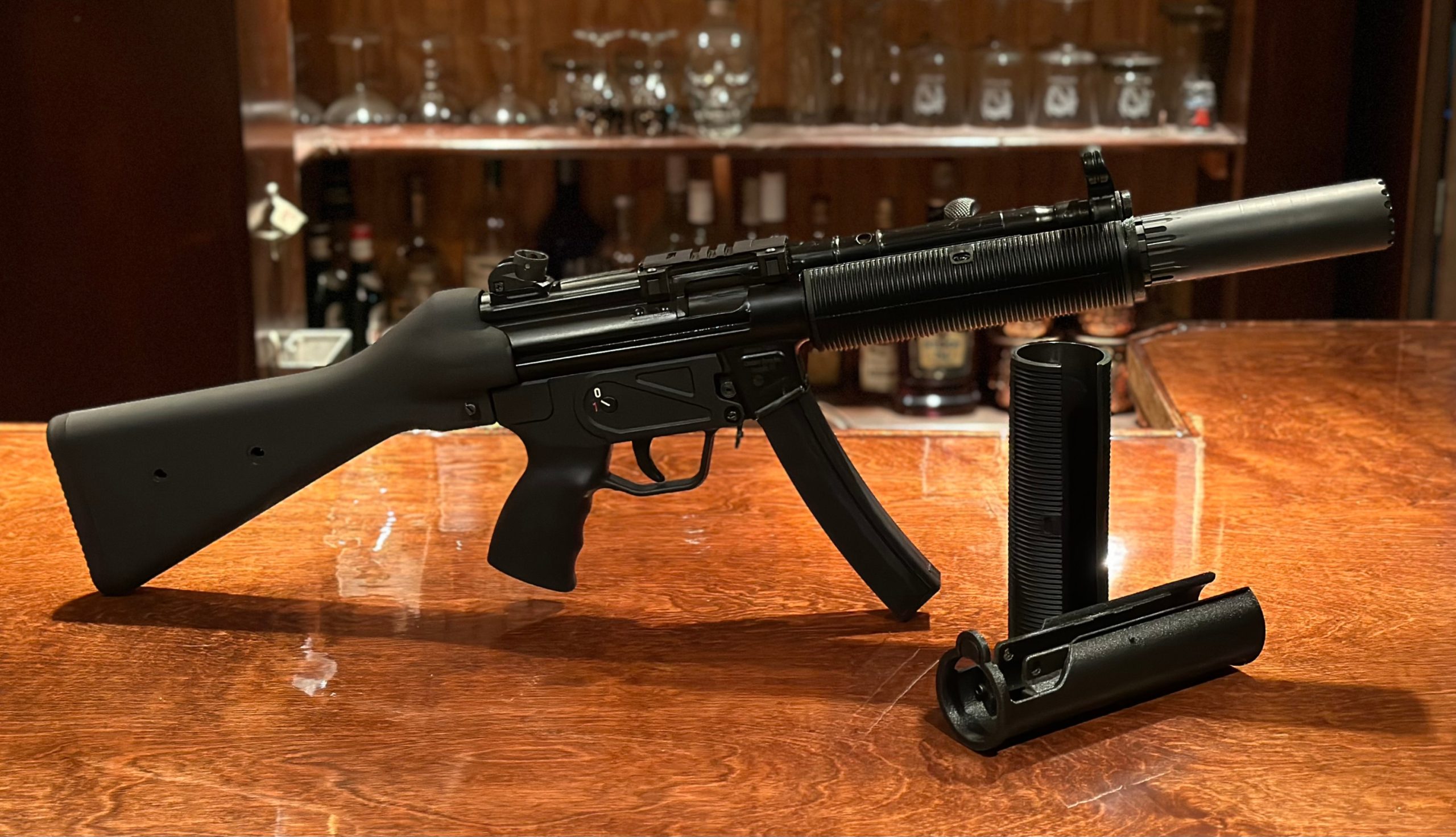 A picture of a fake MP5SD made using a printed adapter, a rubber shroud, and a YHM R9. The MP5 is next to a standalone adapter and a German rubber shroud. The picture can be clicked to take you to the store page to learn more.