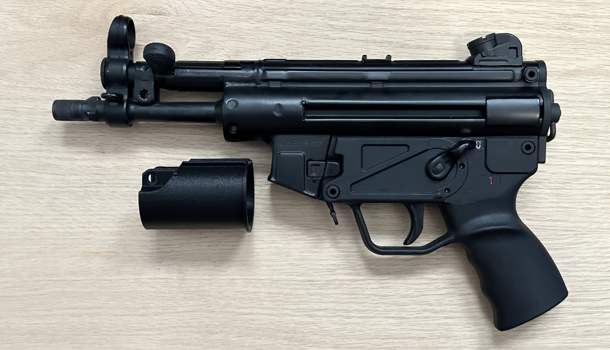 A picture of an MP5K without a handguard. The rear section of the BL-SD adapter is pictured next to it.