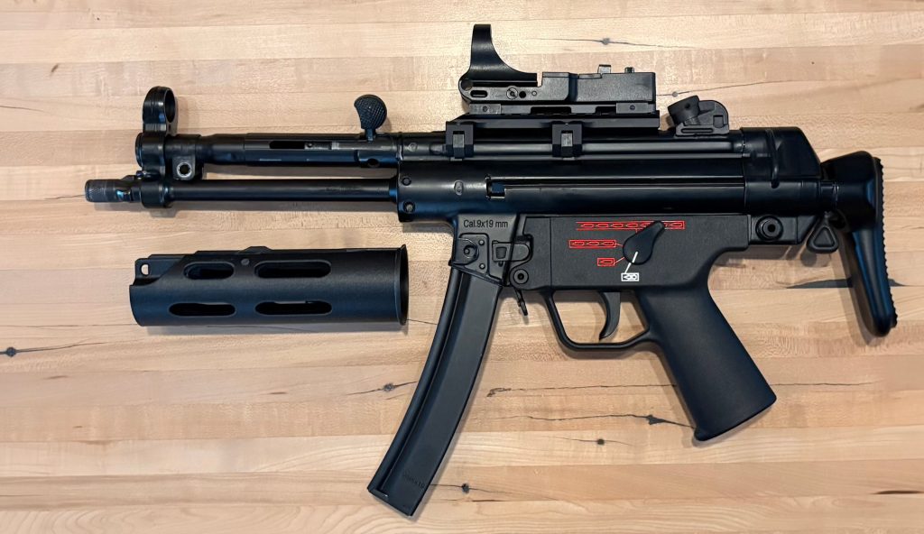 A picture of an MP5 without a handguard. The rear section of the BL-SD adapter is pictured next to it.