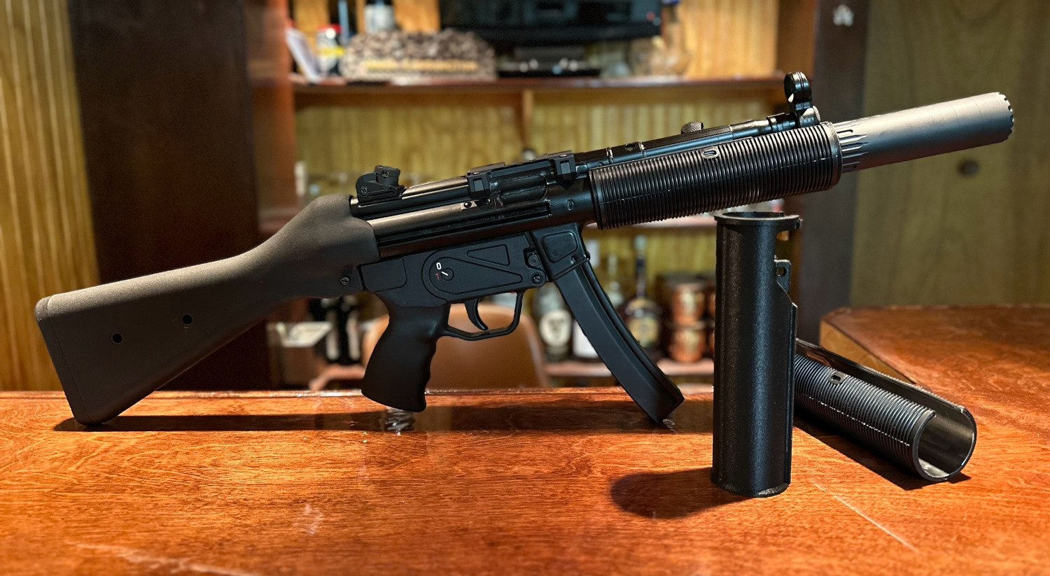 A picture of a fake MP5SD made using a printed adapter, a rubber shroud, and a YHM R9. The MP5 is next to a standalone adapter and a German rubber shroud. The picture can be clicked to take you to the store page to learn more.