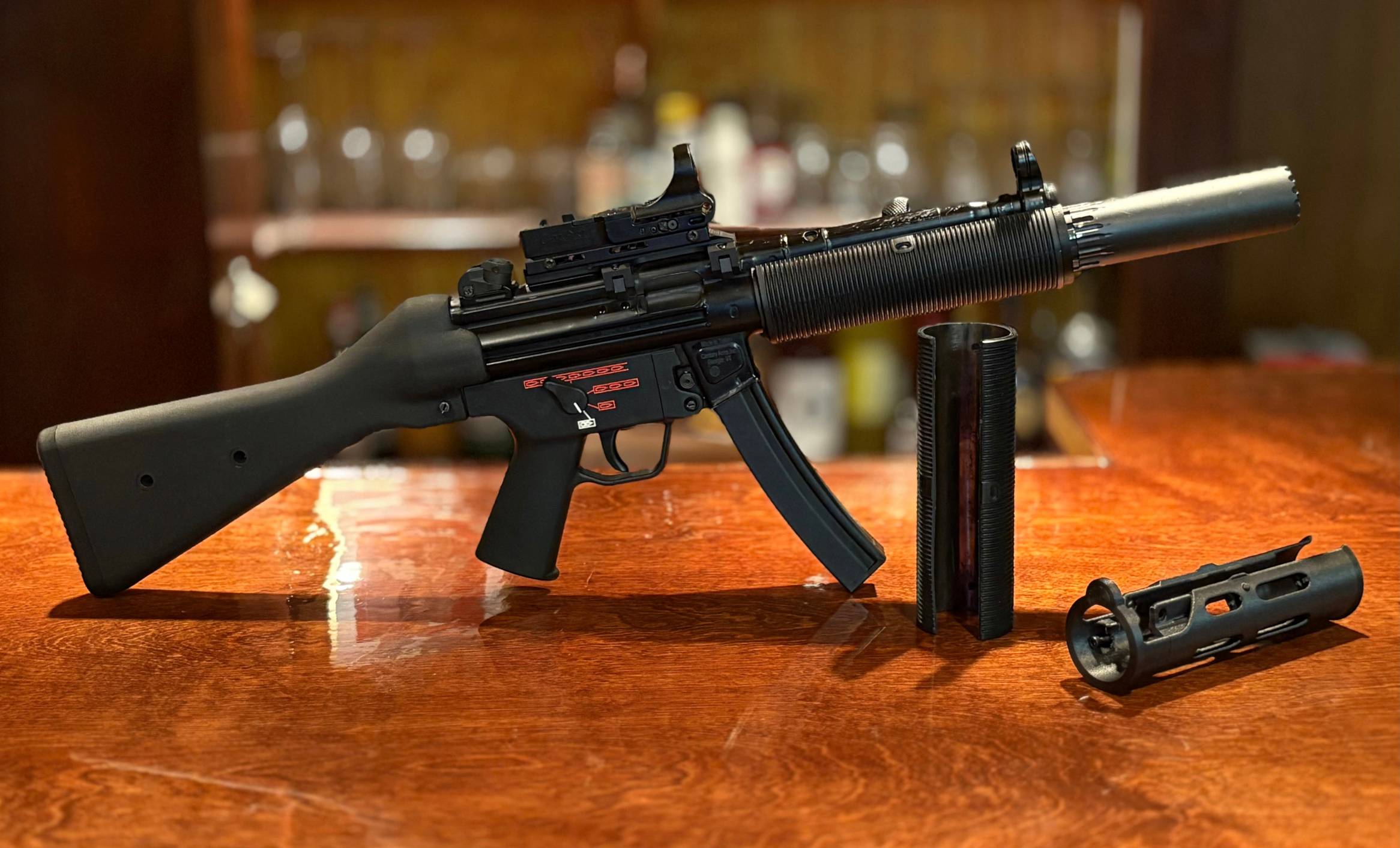 A picture of a fake MP5SD made using a printed adapter, a rubber shroud, and a YHM R9. The MP5 is next to a standalone adapter and a German rubber shroud. The picture can be clicked to take you to the store page to learn more.